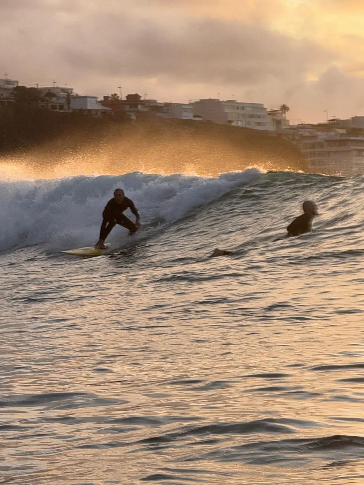 Zwei Surfer auf einer goldenen Welle bei Sonnenuntergang